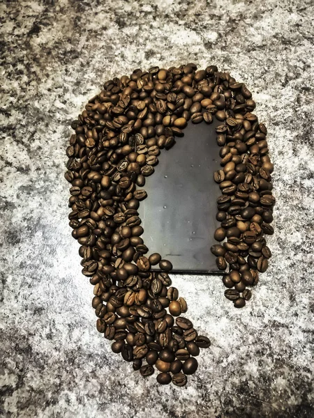 Tezgahın üstünde mermer parçacıklar, kadın saçı şeklinde kahve çekirdekleri ve oval yüz şeklinde koyu çikolata var..