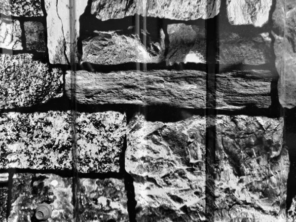 Siyah beyaz duvar, blokların kaba dokusu ayrı parçalara bölünmüş..