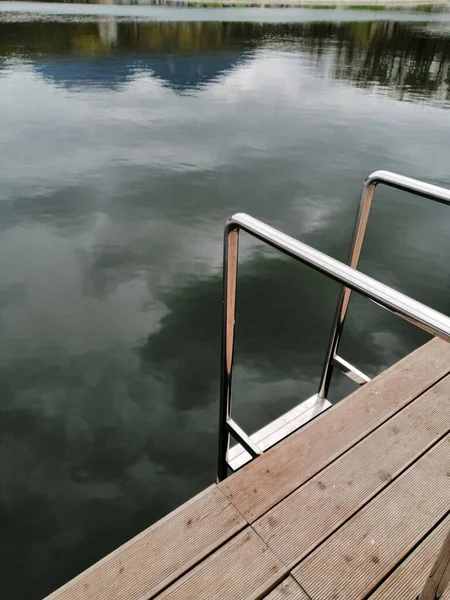 Dekoratif bir gölün arka planı ve ahşap bir köprü ve demir tırabzanlar şeklinde suya küçük bir iniş..