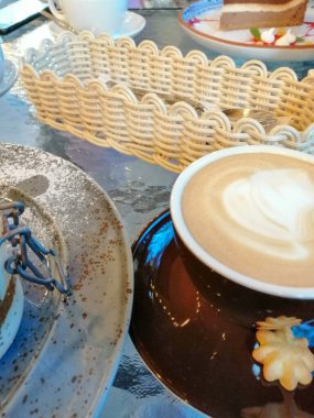 Bir kafede geleneksel masa, tatlı, bir fincan sıcak kapuçino ve kurabiye..