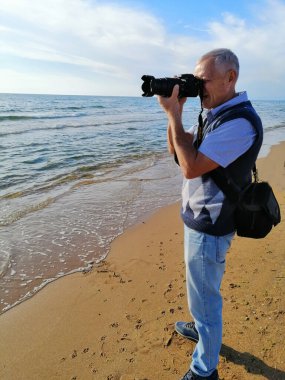 Sahilde kamerayla çekim yapan bir adam..