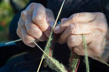 Geleneksel Sırp yün çorapları örmek için iğneler kullanan yaşlı bir kadının eline yakın çekim