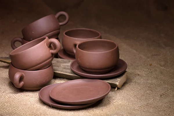 Clay cups and saucers on a sacking about old boards — Stock Photo, Image