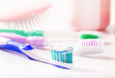 Toothbrushes and hairbrush in pastel tones clipart