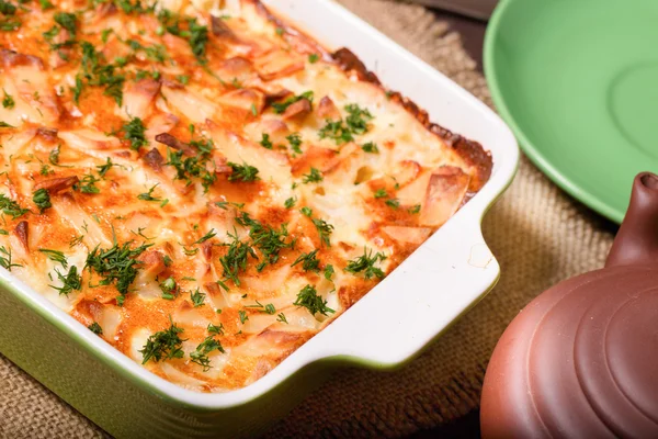 Prato com as batatas cozidas no forno em uma mesa de cozinha — Fotografia de Stock