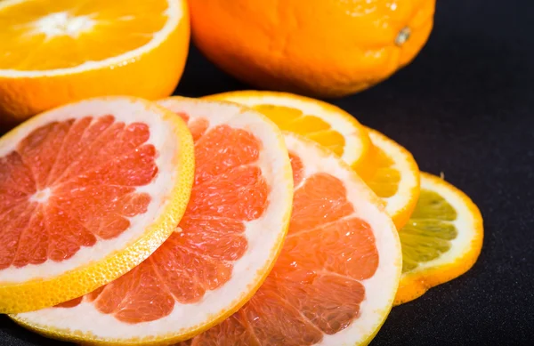 Segmenten van de sinaasappel- en grapefruitsap op een zwarte achtergrond — Stockfoto