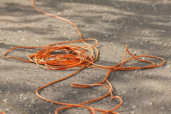 Un long fil électrique orange repose sur l'asphalte — Photo