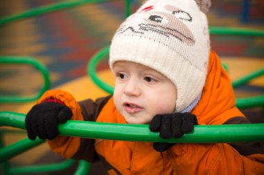 The little boy in a warm cap and a jacket holds an iron hand-rai