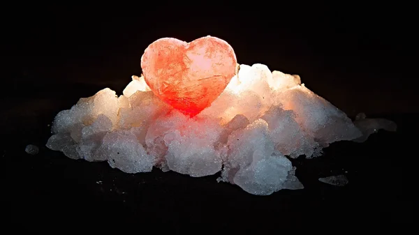 The red ice heart illuminated behind on a hill of white snow — Stock Photo, Image