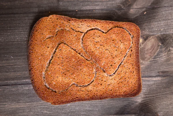 Dois corações que se recortam em um pedaço de pão de centeio — Fotografia de Stock