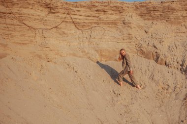 Kumlu tepelerin arasında klasik takım elbiseli sarışın kız.