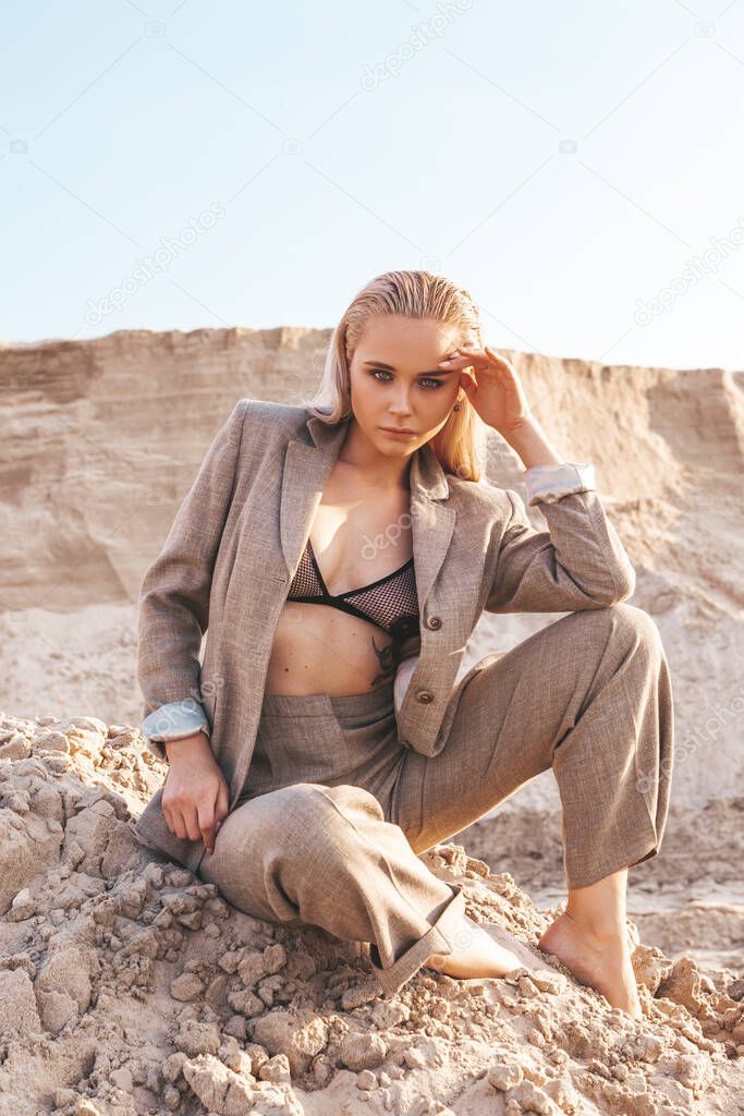 blonde girl in a classic suit among the sandy hills