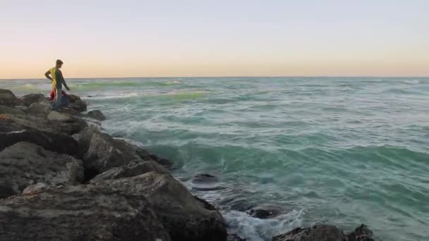 The rocks on the sea shore, the waves, men fish — Stock Video