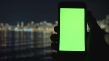 Adamın biri yeşil ekranlı telefonu dışarı kaydırıyor. Ekrana dokunan adam telefonu taklit ediyor
