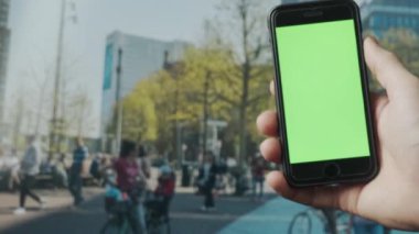 Açık havada yeşil ekranlı akıllı telefon kullanarak erkek elini kapat. 4K