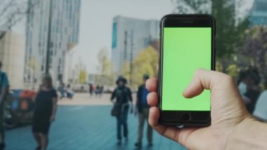 Açık havada yeşil ekranlı akıllı telefon kullanarak erkek elini kapat. 4K