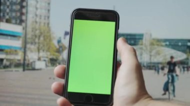 Açık havada yeşil ekranlı akıllı telefon kullanarak erkek elini kapat. 4K