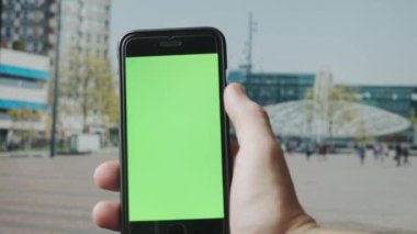 Açık havada yeşil ekranlı akıllı telefon kullanarak erkek elini kapat. 4K