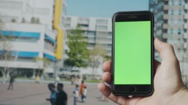 Açık havada yeşil ekranlı akıllı telefon kullanarak erkek elini kapat. 4K