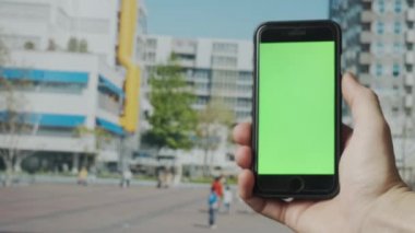 Açık havada yeşil ekranlı akıllı telefon kullanarak erkek elini kapat. 4K