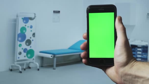 Médico sosteniendo smartphone con maqueta en el gabinete del hospital. Imágenes de 4k — Vídeos de Stock