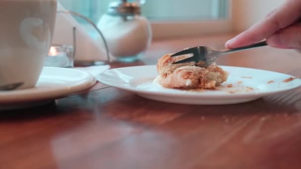 Großaufnahme Ein junger Mann schneidet ein Stück von einem Croissant ab. — Stockvideo