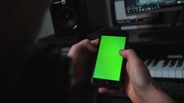 Müzik stüdyosunda yeşil ekranlı telefon kullanan adamı yakın plan çek.