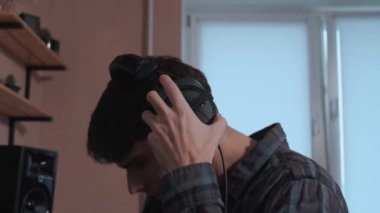 Ses stüdyosu kaydı. Adam müzik stüdyosunda şarkı söylemeden önce kulaklık takıyor..