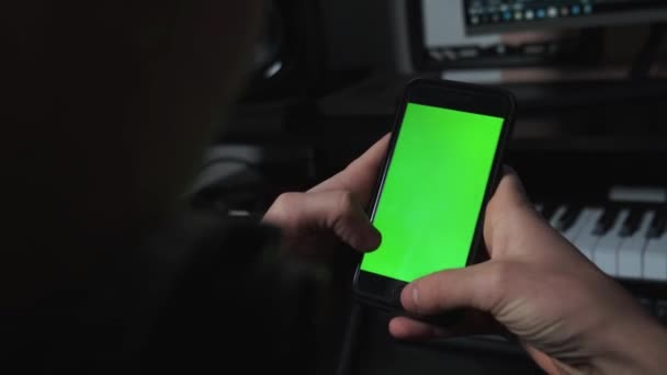 Detailní záběr chlapa v hudebním studiu pomocí telefonu se zelenou obrazovkou — Stock video