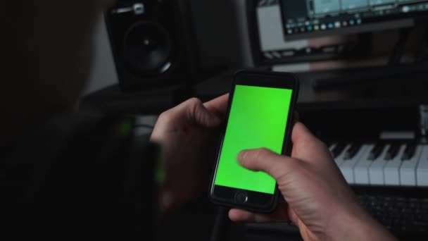 Tæt på skud af fyr i musikstudiet ved hjælp af telefon med grøn skærm – Stock-video