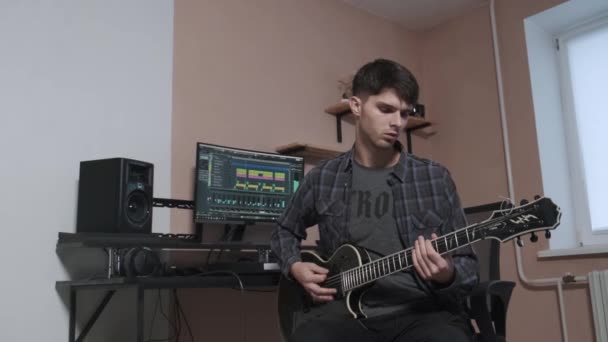 Guitarrista guapo con barba toca guitarra acústica en un estudio de música. Primer plano. — Vídeo de stock