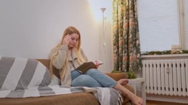 Genç bir kadın sandalyesinde rahatlıyor ve kitabı karıştırıyor..