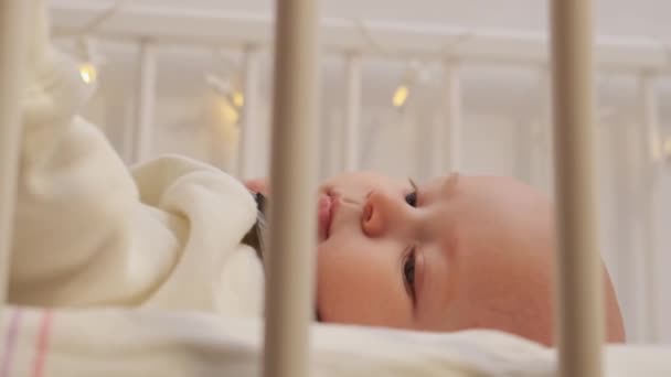 Primer plano pequeño niño. Vista lateral a través del enrejado de la cama. — Vídeos de Stock