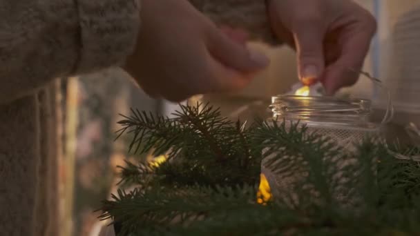 Девушка украшает интерьер новогодней или рождественской композиции свечами. — стоковое видео