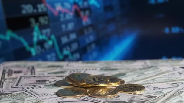 Bitcoin munten tegen de achtergrond van veranderende beurskoersen. — Stockvideo
