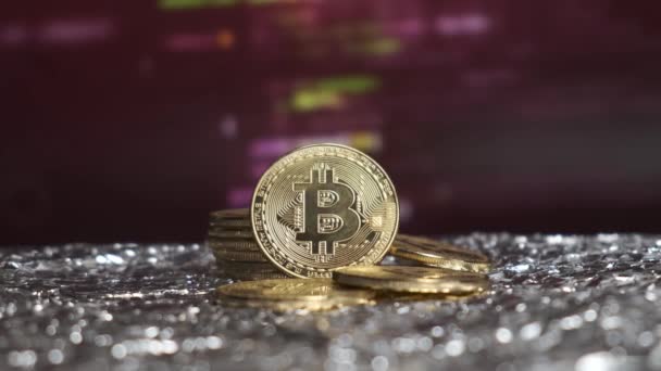 Bitcoin munten tegen de achtergrond van veranderende beurskoersen. — Stockvideo