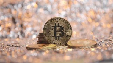 Bitcoin paraları altın tozunun arka planında yatar.