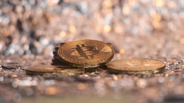 Bitcoin-Münzen liegen vor dem Hintergrund von Goldstaub. — Stockvideo