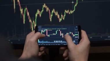 Telefon ve bilgisayar kullanarak bitcoin kripto parası ticareti yapan bir yatırımcı.
