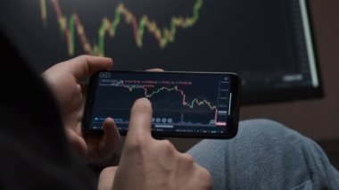 Telefon ve bilgisayar kullanarak bitcoin kripto parası ticareti yapan bir yatırımcı.