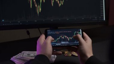 İşadamı cep telefonundaki dijital döviz işlemlerinin Bitcoin fiyat tablosunu kontrol ediyor