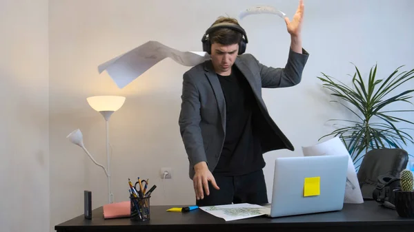 Genç bir uzman müzik dinler ve iş yerinde coşkuyla dans eder..