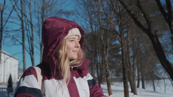 Una chica feliz en manoplas mira a lo lejos en un día de invierno helado. — Vídeo de stock