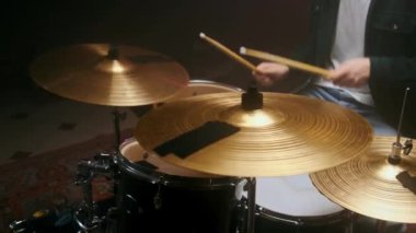 Davulcu, siyah bir arkaplanda karanlık bir odada davul çalıyor..
