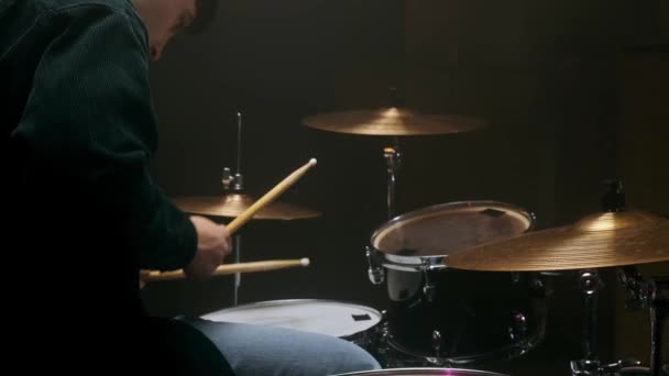 Schlagzeuger spielt Schlagzeug in einem dunklen Raum auf schwarzem Hintergrund. — Stockvideo