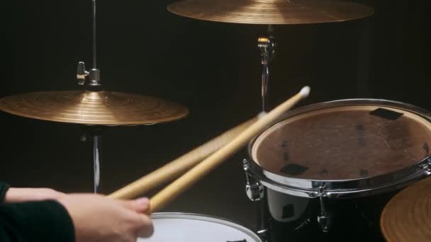 Baterista tocando o tambor em um quarto escuro em um fundo preto. — Vídeo de Stock