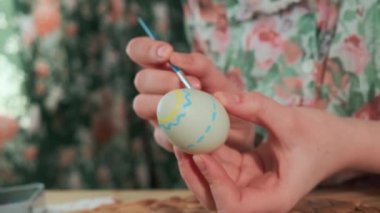 Kadın, Paskalya yumurtalarını renkli boyalarla boyuyor, yakın plan.