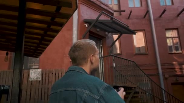 Un joven viajero toma fotos de un edificio de ladrillo rojo en un casco antiguo — Vídeo de stock