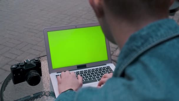 De fotograaf werkt op een laptop en zit in een koffieshop. — Stockvideo