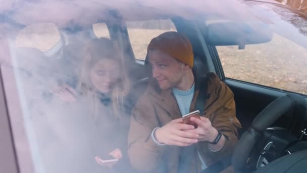 Un paio di viaggiatori seduti in macchina in cerca del telefono che tiene il percorso — Video Stock